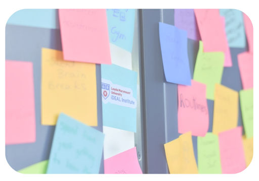 Post-It Notes on a wall surrounding the iDEAL Institute's Logo